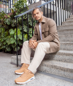 Man sat on steps wearing the latest sketchers in a summer outfit